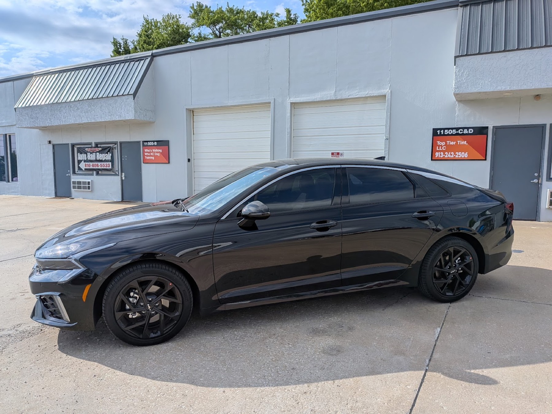 Blacked-out Kia K5 with fresh window tint outside the Top Tier Tint shop in Olathe, Kansas
